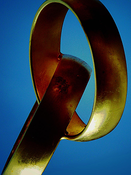 Verschlungene goldene Eheringe vor blauem Hintergrund